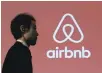  ?? — Reuters ?? A man walks past a logo of Airbnb in Tokyo, Japan.