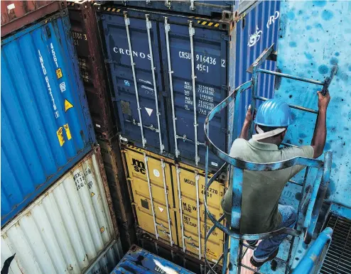  ?? SANJIT DAS / BLOOMBERG FILES ?? A worker descends a gantry crane ladder beside stacked containers in Haldia, India. The subcontine­nt — not China — is the world’s fastest-growing large economy, Andrew Coyne says, and perhaps a better choice for a trade deal.