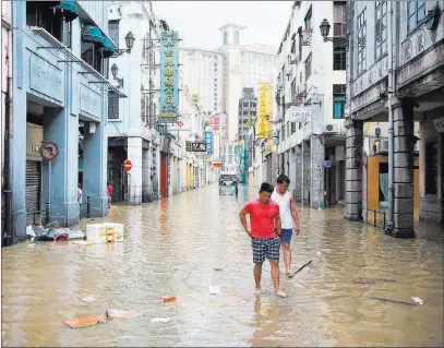  ??  ?? Pedestrian­s walk on a flooded road Wednesday caused by Typhoon Hato in Macau, China. The Associated Press
