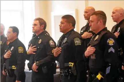  ?? PETE BANNAN — DIGITAL FIRST MEDIA ?? Chester County police officers hold their hands to their hearts during the singing of the National Anthem at Chester County District Attorney awards at the Historic Chester County Courthouse.