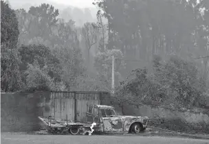  ??  ?? A burnt truck stands next to a gate Monday in the village of Pobrais, near Pedrogao Grande. More than 2,000 firefighte­rs in Portugal battled to contain major wildfires in the central region of the country, while authoritie­s came under mounting...