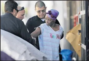  ?? Mark Boster Los Angeles Times ?? OFFICERS arrest a homeless woman on 5th Street during a skid row cleanup in 2016. Police made 14,000 arrests of homeless people in L.A. that year — often for failure to appear in court for an unpaid citation.