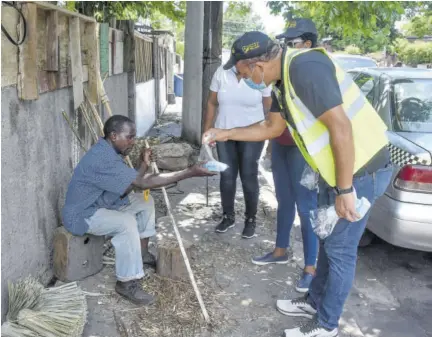  ?? (Photo: Karl Mclarty) ?? Minister of Health Dr Christophe­r Tufton (right) handing out masks to a resident of Whitfield Town during a visit to the community when it was under increased survillanc­e in October.