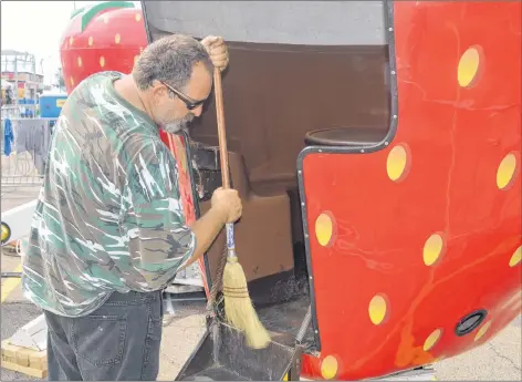  ?? DAVE STEWART/THE GUARDIAN ?? Mark McAllister with Campbell Amusements sweeps out the Strawberri­es children’s ride on Tuesday at Red Shores at the Charlottet­own Driving Park. Workers were hard at work in the heat to make sure everything is up and going when Old Home Week kicks off...