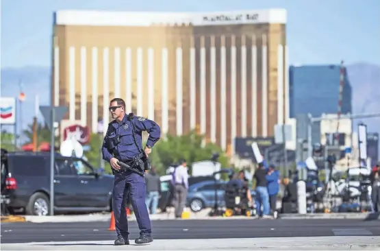  ?? TOM TINGLE/THE REPUBLIC ?? A Nevada Highway Patrol trooper stands at a roadblock on Las Vegas Boulevard and Sunset Road with Mandalay Bay in the background on Monday morning.