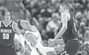  ?? DAVID ZALUBOWSKI/AP ?? Thunder forward Isaiah Roby, front left, falls after running into Nuggets center Nikola Jokic, right, in the second half of Denver’s 113-107 win Saturday night.