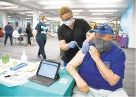  ?? PAUL W. GILLESPIE/CAPITAL GAZETTE ?? Joi Remoll gives Ron Jones a dose of the Johnson & Johnson vaccine May 20. The Anne Arundel County Library partnered with Luminis Health to hold a COVID-19 vaccinatio­n clinic at the Discoverie­s branch in the Westfield Annapolis Mall.