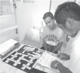  ??  ?? A policeman documents shabu sachets, worth about P300,000, and a gun seized from drug trading suspect Leovan Chiu (seated), elder brother of incumbent Tinago Councilman Francis Chiu.