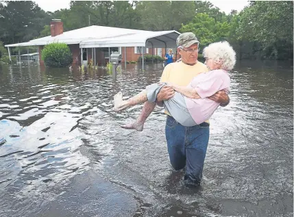  ?? Joe Raedle, Getty Images ?? Bob Richling carries Iris Darden as water from the Little River starts to seep into her home on Monday in Spring Lake, N.C.