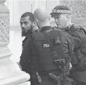  ?? NIKLAS HALLE’N / AFP / GETTY IMAGES ?? British police officers detain a man near Downing Street and the houses of Parliament in central London on Thursday. The man, who was under surveillan­ce after a tip from his family, was carrying a number of knives.