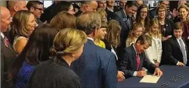  ?? AJC 2019 ?? Gov. Brian Kemp, flanked by children, parents, lawmakers and educators, signed a new dyslexia screening mandate in a 2019 ceremony at Wheeler High School. The law was approved Thursday in a unanimous vote by the Georgia Board of Education.