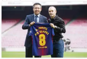  ??  ?? FC Barcelona’s Andres Iniesta, right, and FC Barcelona’s President Josep Maria Bartomeu pose with a shirt reading in Catalan: “Andres Iniesta forvever” at the Camp Nou stadium in Barcelona, on Friday. (AP)