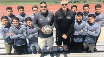  ?? Eric Sondheimer Los Angeles Times ?? A STRICT grades policy enforced by Downey High soccer coach Marvin Mires, with ball, helped 13 of his players get into four-year colleges. He is shown with 11 of the players and assistant coach Ian McFayden.