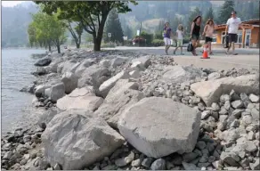  ?? GARY NYLANDER/The Daily Courier ?? People walk along the Peachland waterfront Tuesday. Boulders intended to prevent erosion of a popular lakeshore walkway have significan­tly reduced beach access.