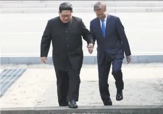  ?? Korea Summit Press Pool ?? In a prelude to an arms summit, North Korean President Kim Jong Un (left) and South Korean leader Moon Jae-in step across the Military Demarcatio­n Line that divides their countries.