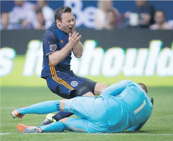 ?? — THE CANADIAN PRESS ?? New York City FC’s Tommy McNamara, back, reacts after a collision with Whitecaps’ Kendall Waston, not seen, as goalkeeper David Ousted grabs the ball during Wednesday’s game in Vancouver. McNamara was barely touched but the play led to a penalty kick...