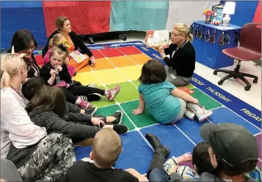  ?? Photo submitted ?? Grace Davis, right, reads to a group of students at Allen Elementary School last fall. Davis, who serves as director of teacher quality and community relations for the Siloam Springs School District, is retiring after 28 years in education.