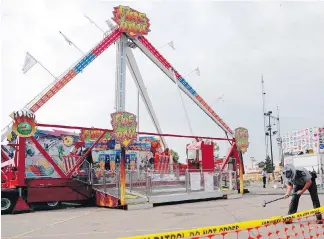  ??  ?? An Ohio State Highway Patrol trooper removes a ground spike from in front of the “Fire Ball” ride at the Ohio State Fair on Thursday.