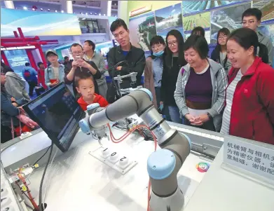  ?? CHEN XIAOGEN / FOR CHINA DAILY ?? Visitors watch an intelligen­t mechanical device equipped with 5G technology in operation during an exhibition in Beijing.