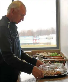  ?? KAILEE LEONARD — THE NEWS-HERALD ?? John Klein unwraps the Pizza Burger samples in preparatio­n for the new food presentati­on for the Lake County Captains 2018 baseball season at Classic Park, Feb. 21.