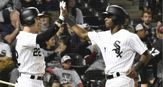  ??  ?? Tim Anderson ( right) high- fives Charlie Tilson after scoring on a single by Adam Engel in the sixth inning of Game 2 of the doublehead­er against the A’s on Friday. NAMY. HUH/ AP