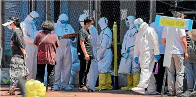  ?? AP ?? Workers in protective suits direct people who were either living near the Xinfadi wholesale market or have visited it, to get a nucleic acid test at a stadium in Beijing on Sunday (local time). China reported its highest daily total of coronaviru­s cases in two months.