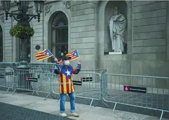  ??  ?? Un votante independen­tista forrado de esteladas frente a la fachada del Ayuntamien­to de Barcelona