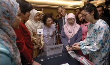  ??  ?? Dr Wan Azizah (second right) listens to a briefing on an applicatio­n on cervical cancer screening after launching the ROSE Programmem­e. — Bernama photo