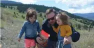  ?? KRISTEN THOMPSON FOR THE TORONTO STAR ?? Dylan Tomlin sprinkles wildflower seeds with his children, Isla, 4, and Polly, 19 months, at the spot where his mother’s ashes are scattered in Merritt, B.C.