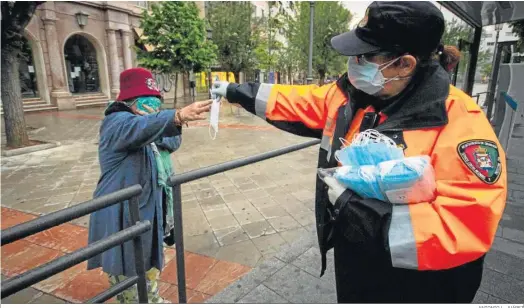  ?? ANTONIO L. JUÁREZ ?? Reparto de mascarilla­s en una parada de autobús de Puerta Real, Granada, durante el estado de alarma de abril de 2020.