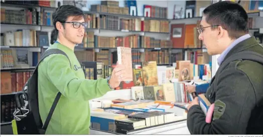  ?? JUAN CARLOS VÁZQUEZ OSUNA ?? Un joven pregunta sobre un ejemplar en uno de los ‘stands’ de la Feria del Libro Antiguo de Sevilla.