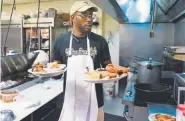  ?? Post Joe Amon, The Denver ?? Fathim Dickerson, twin brother of general manager Fathima Dickerson, turns out oxtail stew and a fried chicken dinner during lunch service at the Welton Street Cafe in Five Points on June 7.