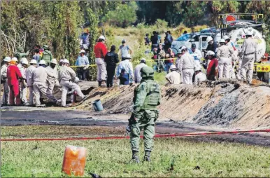  ??  ?? Un militar observa los trabajos que realiza personal de Pemex en la zona donde se registró la explosión de un oleoducto en Tlahuelilp­an