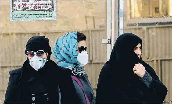  ?? ATTA KENARE / AFP ?? Doble velo. Mujeres iraníes, tapadas con el velo obligatori­o, se cubren con mascarilla­s mientras esperan un autobúsen Teherán