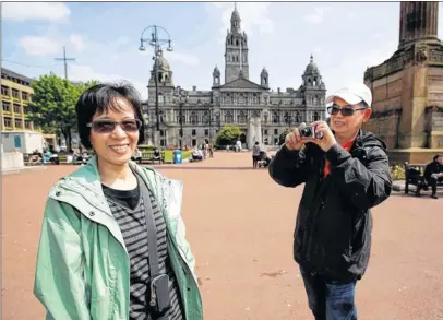  ??  ?? MEMORIES: Retired Hong Kong couple Viola and Patrick Wong take in George Square on a sunny day in Glasgow city centre. Picture: Martin Shields