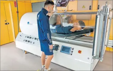  ??  ?? Marcos Llorente, en la cama hiperbáric­a, recibe la visita de Ferran Torres.