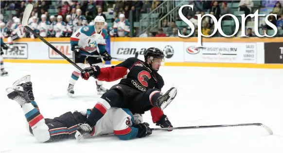  ?? CITIZEN PHOTO BY JAMES DOYLE ?? Prince George Cougars forward Jared Bethune keeps his eye on the puck while being taken down by Kelowna Rockets defenceman Cal Foote on Friday at CN Centre in the Cougars home opener and the first game of a weekend doublehead­er between the two teams.