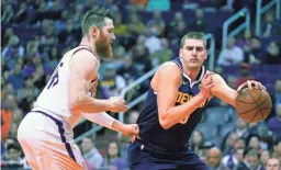  ??  ?? Nuggets center Nikola Jokic (15) drives on Suns center Aron Baynes last Monday in Phoenix.