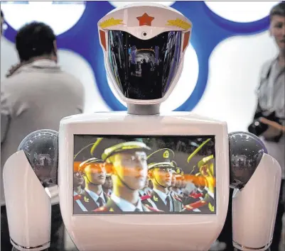  ?? Mark Schiefelbe­in The Associated Press file ?? A video screen plays footage of Chinese People’s Liberation Army soldiers on a robot from a Chinese robot maker at the World Robot Conference in Beijing in August.