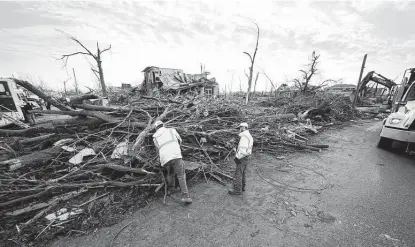  ?? Gerald Herbert / Associated Press ?? Workers cut through debris in the aftermath of tornadoes that tore through Mayfield, Ky., which suffered some of the worst damage in the country amid the tornado outbreak.