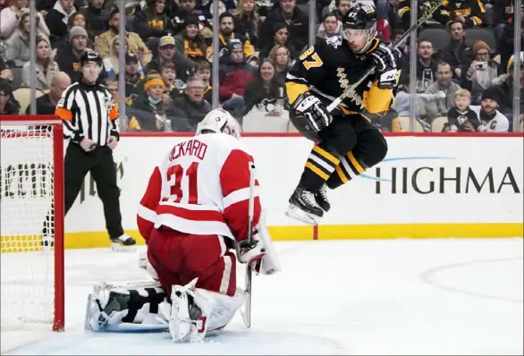  ?? Associated Press photos ?? Sidney Crosby leaps to avoid a shot on Red Wings goaltender Calvin Pickard in the second period.