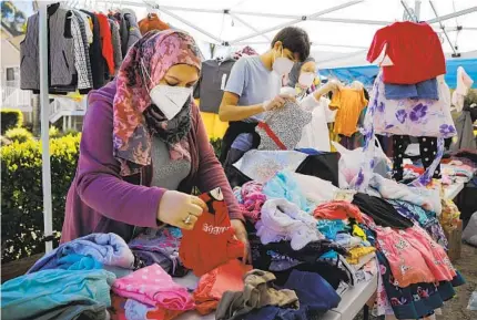  ?? K.C. ALFRED U-T ?? Zulfar Shaker (left) and other volunteers from the San Diego Afghan Refugees Aid Group sort through clothes during a distributi­on event in La Jolla. Clothing, food and toys were available for families that have been living in hotels.