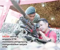  ??  ?? SALAH seorang anggota ATM membantu pengunjung mengendali­kan senjata ATM.