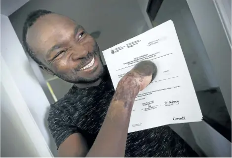  ?? JOHN WOODS/THE CANADIAN PRESS ?? Seidu Mohammed smiles as he shows off his refugee claim acceptance letter in Winnipeg on Thursday.