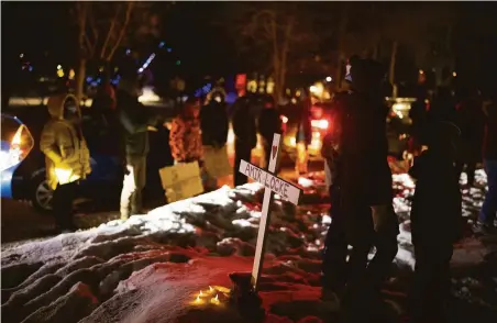  ?? Jeff Wheeler / Star Tribune ?? People gather by a cross commemorat­ing Amir Locke, 22, on the street where the Minneapoli­s acting police chief lives.