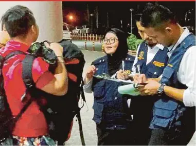 ?? PIC COURTESY OF TAWAU HEALTH OFFICE ?? Tawau Health Office enforcers issuing a compound to a smoker at Tawau Airport on Wednesday.