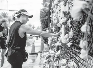  ?? SCOTT MCINTYRE/THE NEW YORK TIMES ?? Marisa Arnolf-Stuzberche­r pauses before a flyer for a missing Champlain Towers South resident she knows Saturday in Surfside, Fla. A fire deep in the rubble of the collapsed building is hampering rescue efforts.