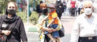  ?? Agence France-presse ?? ↑
Iranians, wear face masks, to fight the coronaviru­s as they walk in Tehran on Saturday.