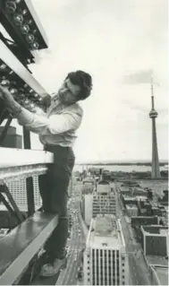  ?? TORONTO STAR ARCHIVES ?? Workmen lay the last stones on the Canada Life Building, which, at 15 storeys, was the city’s tallest building in 1931. Alex Prosser, right, makes sure bulbs on the beacon burn brightly in 1980.