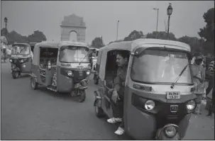  ?? The Associated Press ?? SMOG: Sarwan Singh, an auto-rickshaw driver, waits for passengers near the India Gate monument on Nov. 16 in New Delhi. Singh has been ferrying passengers in his three-wheeled motorized rickshaw for 20 years, working 10 to 12 hour days. He said he...